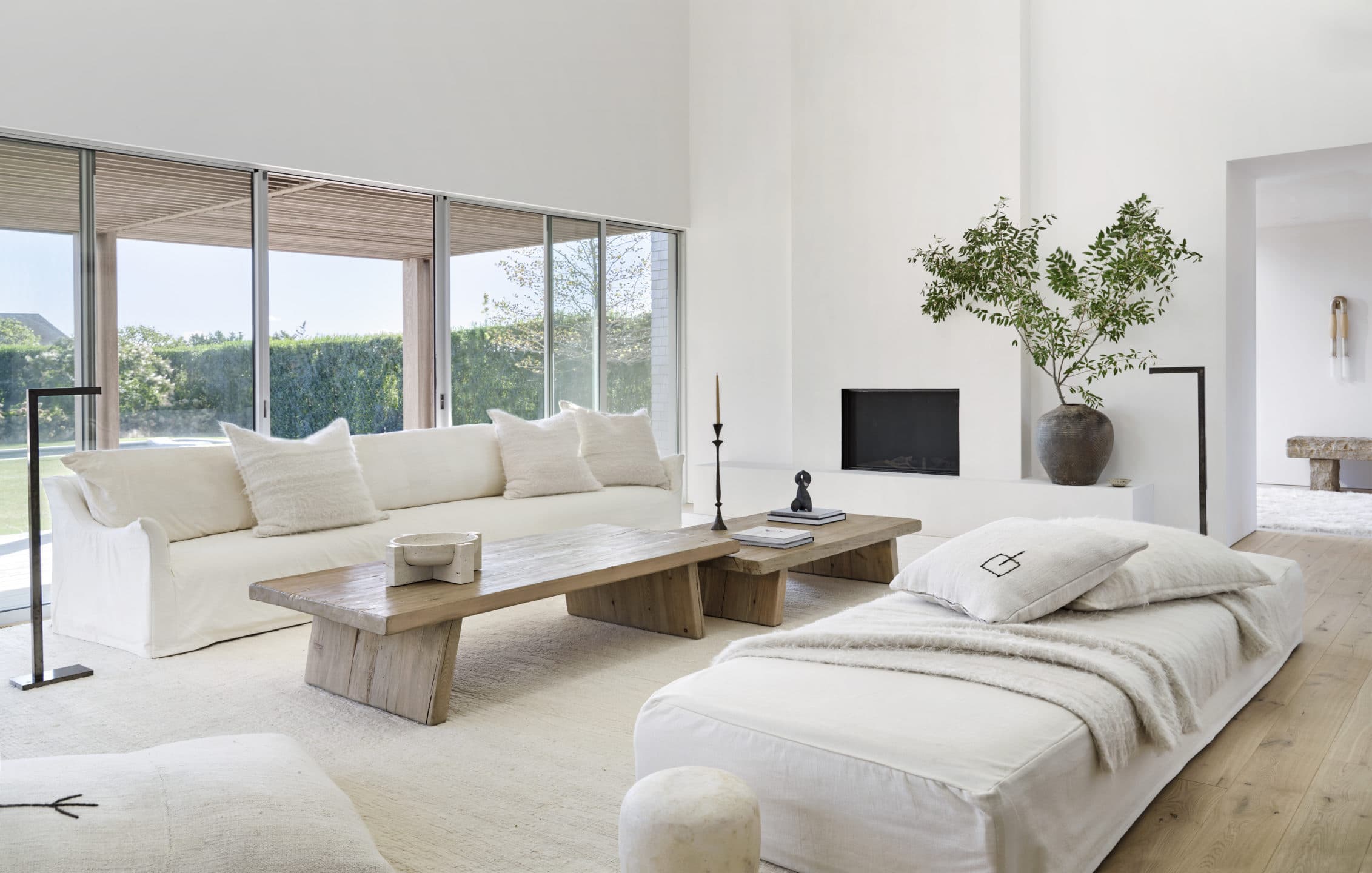 Sunlit living room with long linen sofas, a low oak coffee table and a view to the covered porch