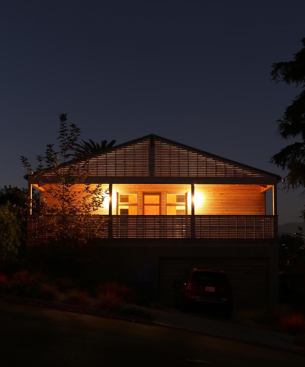 Gabled house glowing at night on its hillside at Abbott Hill House, Highland Park