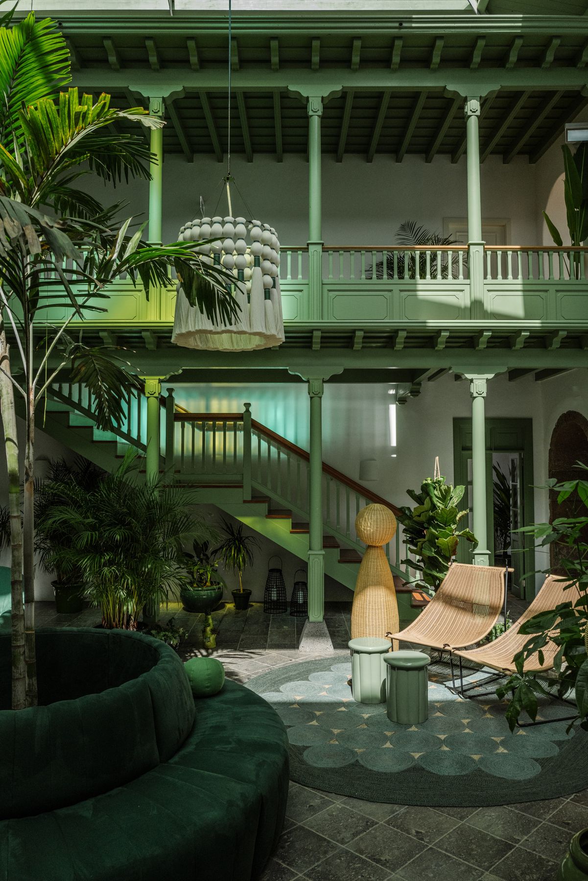 Green galleried courtyard with palms, a pendant lamp and sling chairs at Cesar Lanzarote, Lanzarote