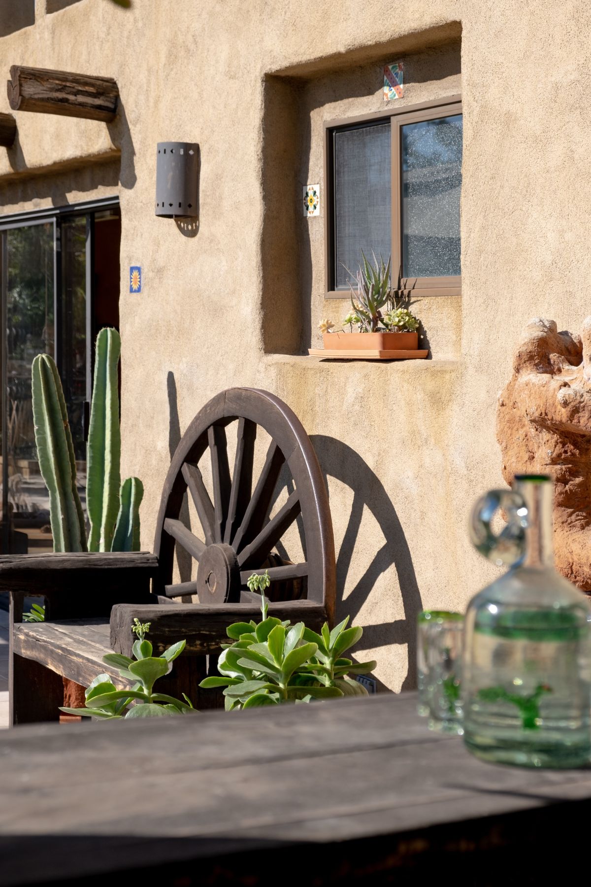 Wagon wheel, cactus and an adobe wall with a deep-set window on the patio at La Esperanza Ranch, Topanga Canyon
