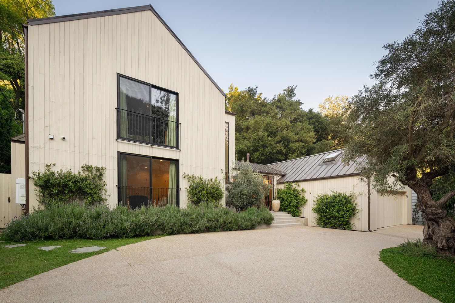 Gabled facade with tall windows above a curving driveway at Mandeville Ranch Revival, Brentwood