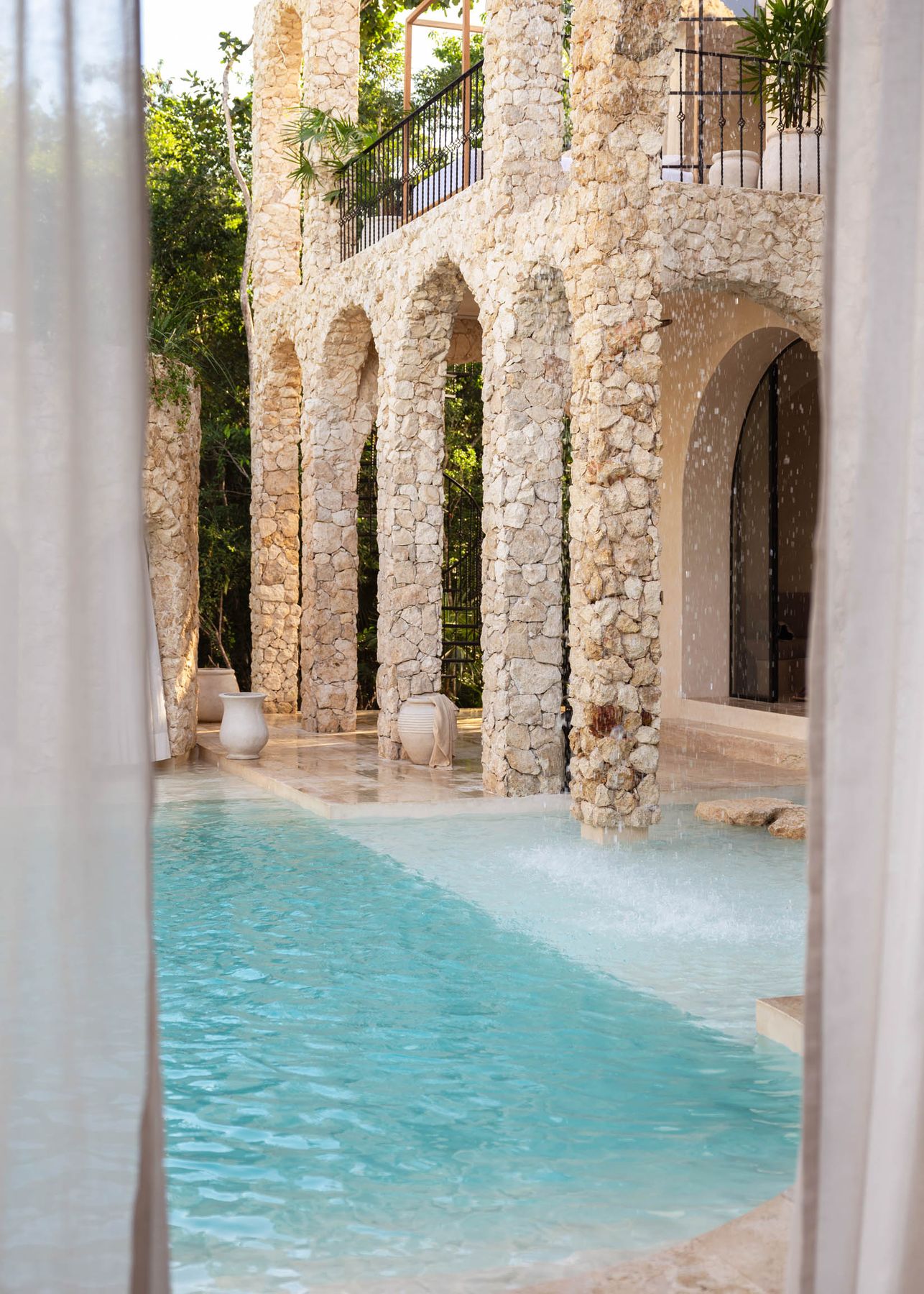 Stone arcade rising above a turquoise pool at Casa Arka, Tulum