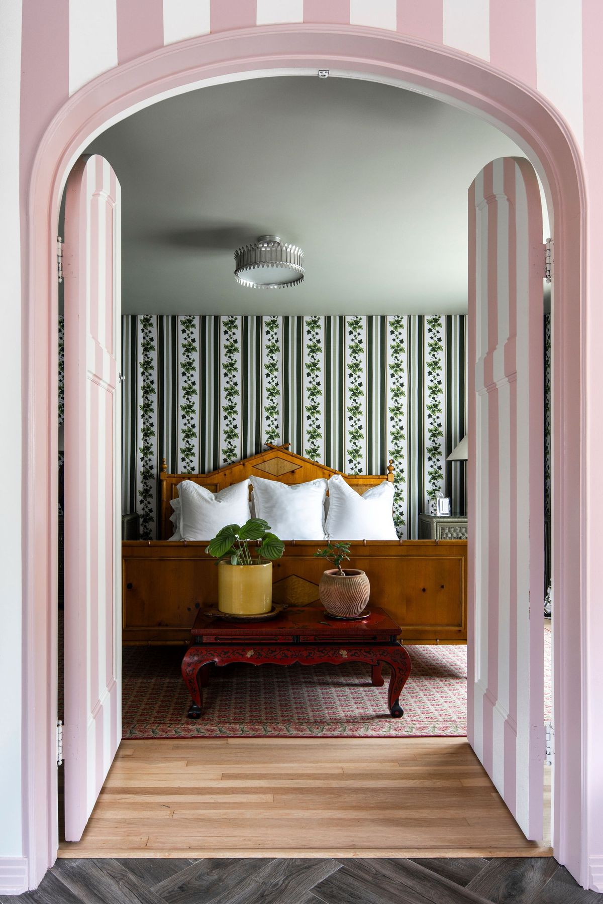 Pink-striped arched doors opening onto a bedroom with trellis wallpaper at Casa Corazón, Hollywood Hills
