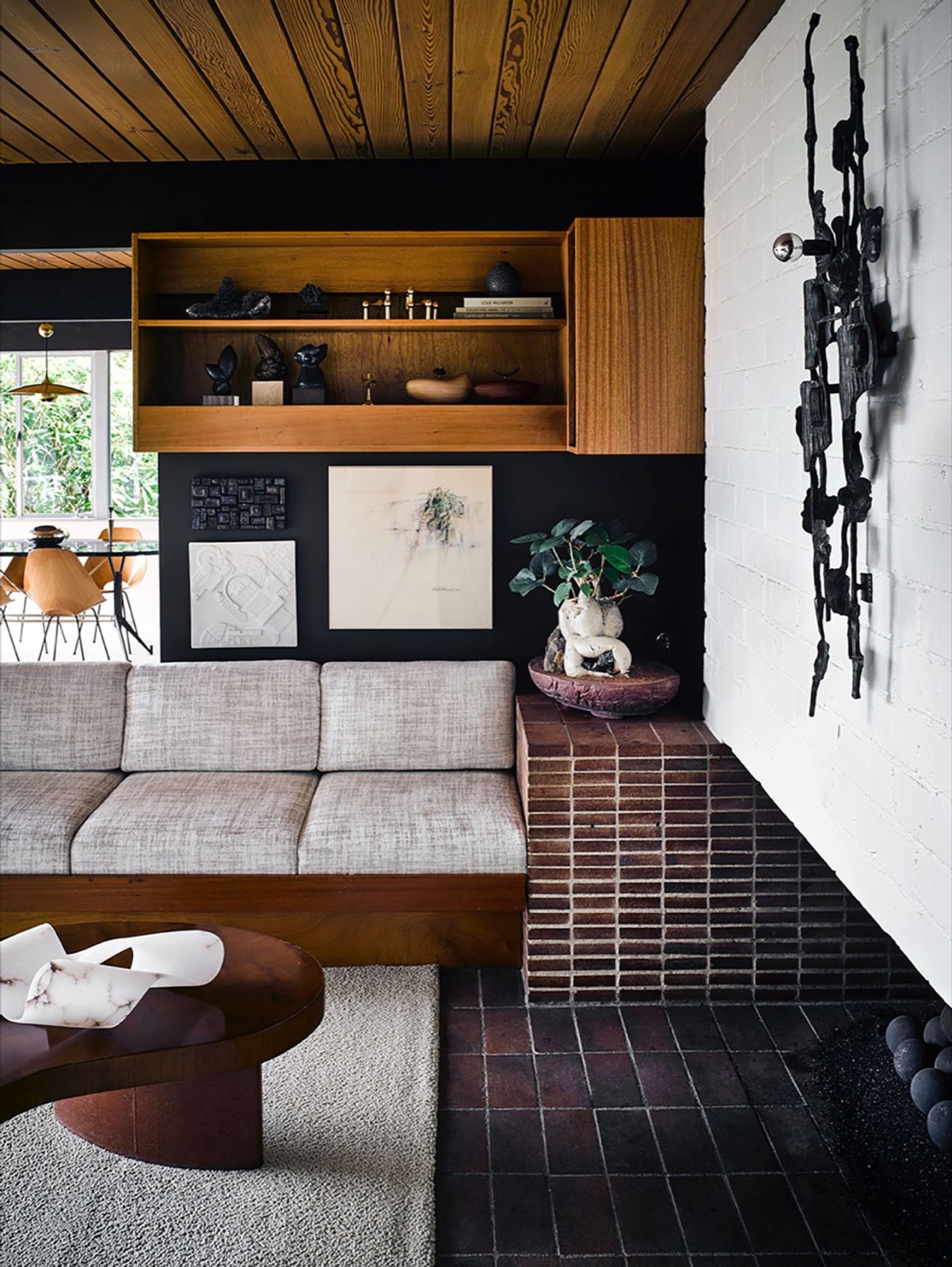 Living room with a black lava-stone wall and a sculpture at Hailey Residence