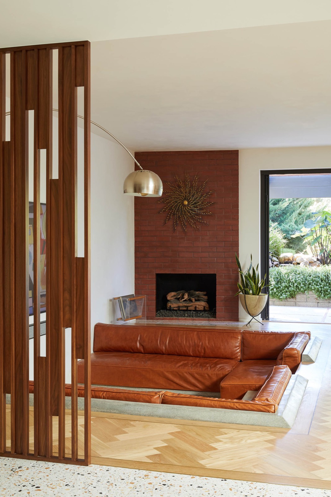 Sunken living room with walnut screen and brick fireplace at Merck House