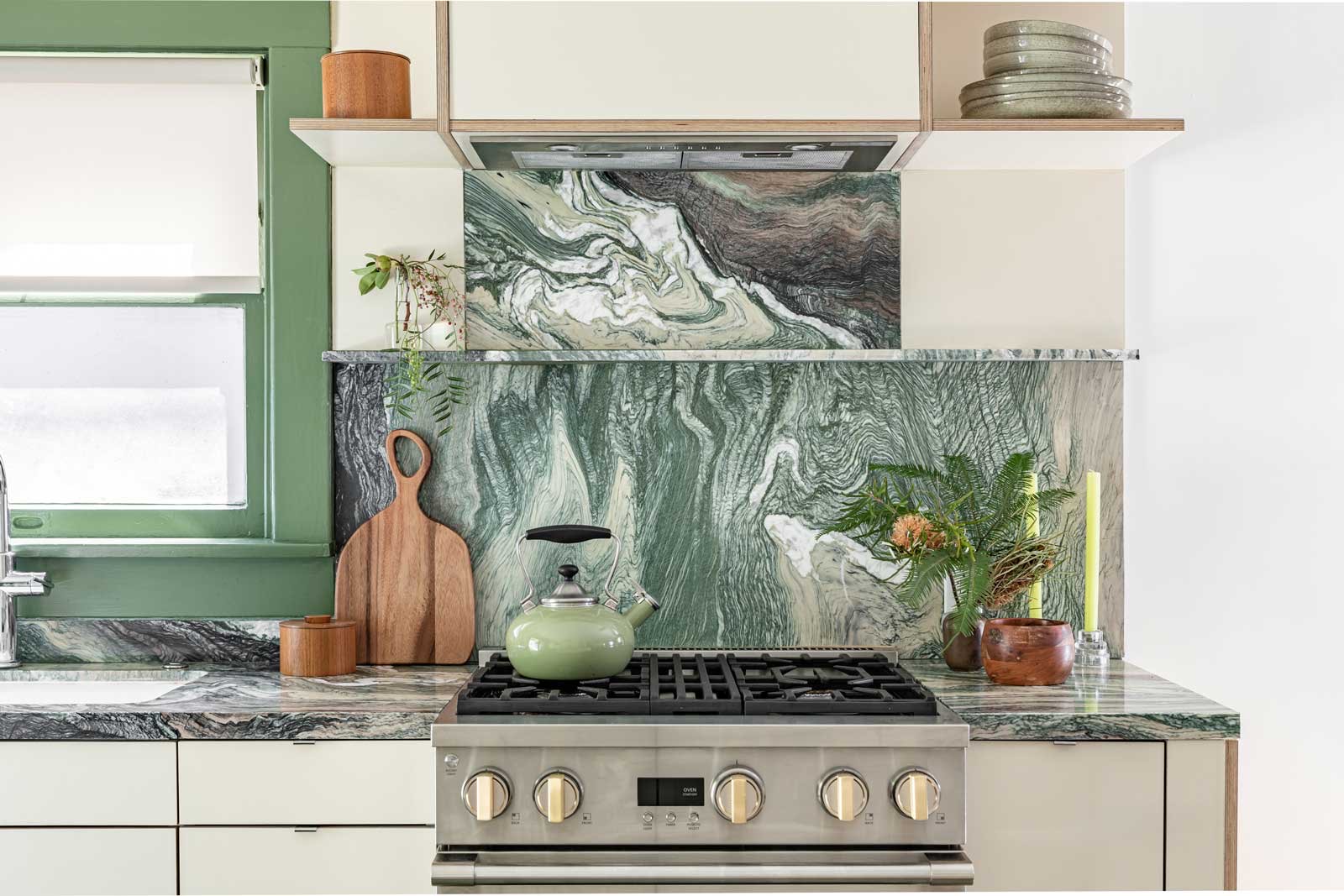 Bach House kitchen with cream cabinetry, green accents, verde marble backsplash and open shelf island — production location in Los Angeles, California