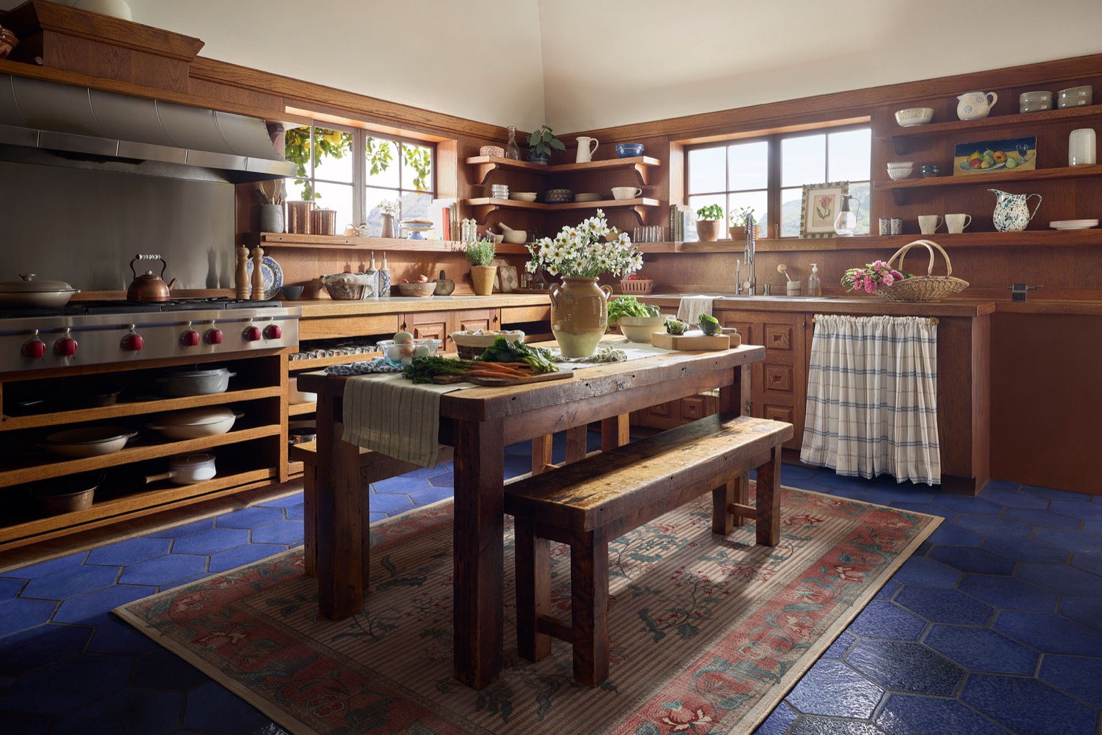 Casa El Greco kitchen with cobalt blue hexagonal tile floor, warm wood millwork, open shelving, and a Wolf range, Santa Monica