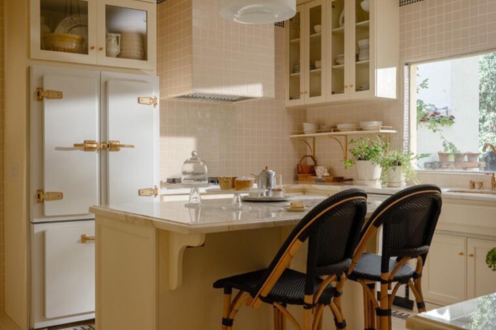 1931 kitchen with cream cabinetry, grid tile, brass hardware and a vintage refrigerator at the Ficker House, Claremont