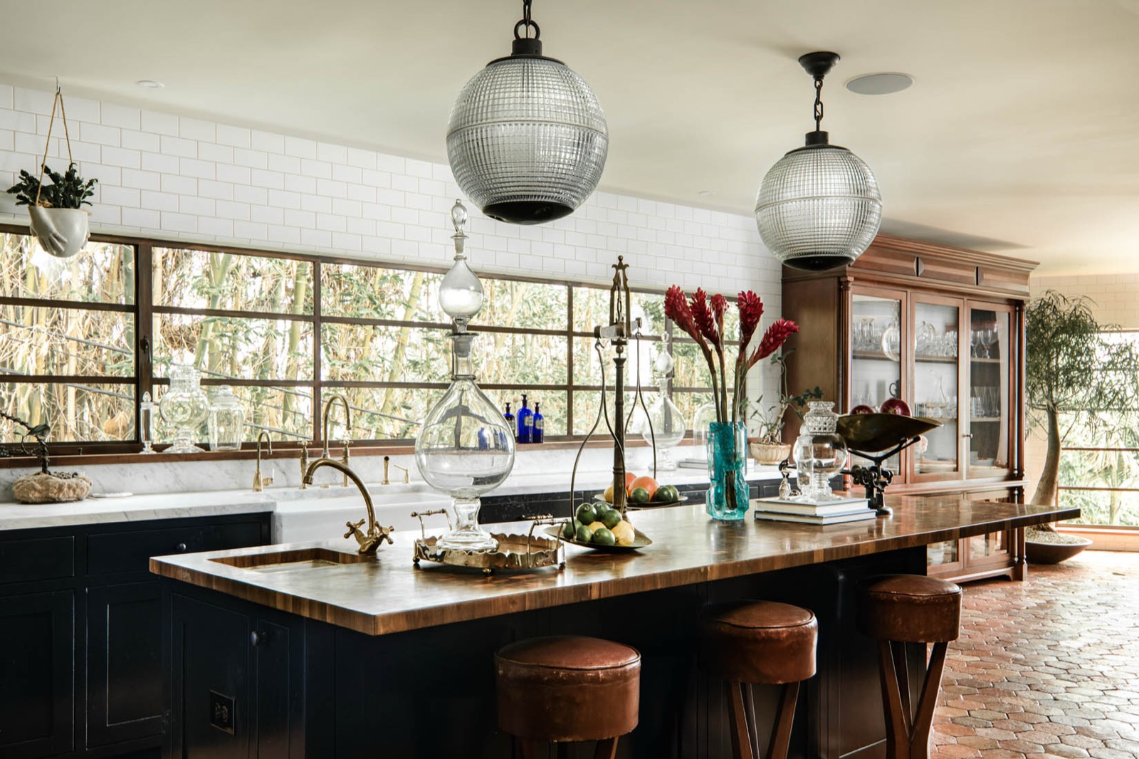 Kings Road kitchen with navy cabinetry, brass fixtures, butcher block island and globe pendants — production location in Los Angeles, California