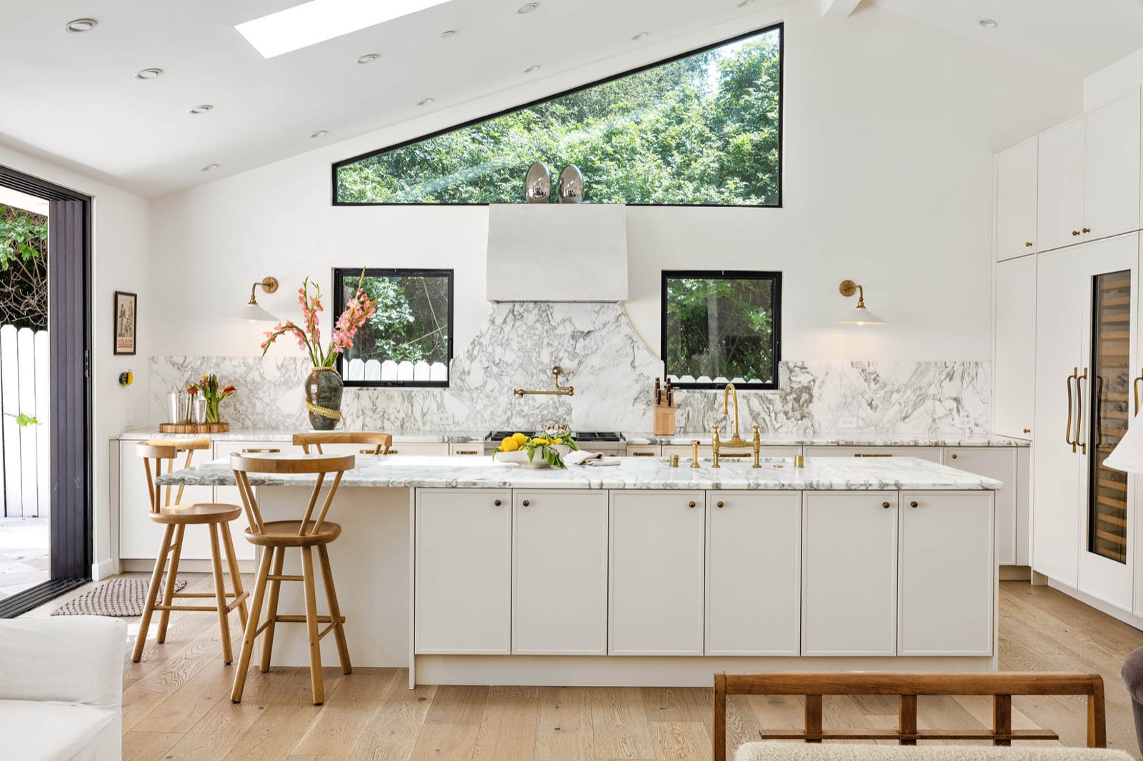 Kitchen with marble counters, brass fixtures and a clerestory window at Mandeville Ranch Revival, Brentwood