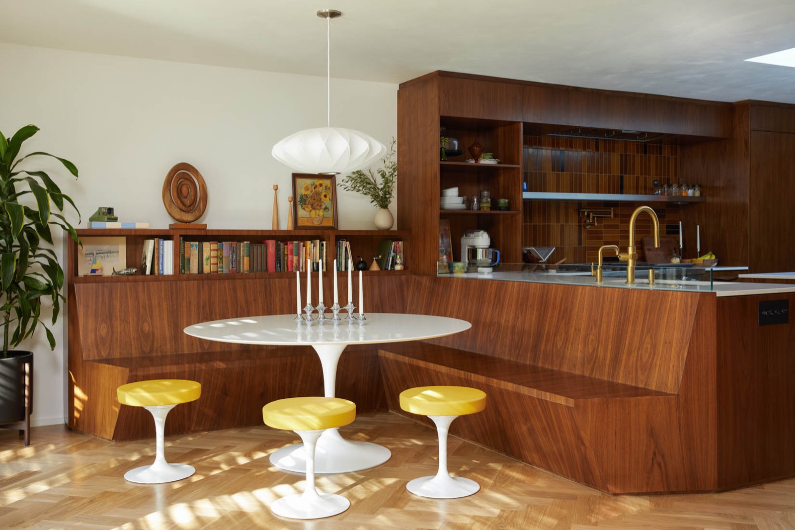 Merck House kitchen with walnut millwork, tulip table, ochre stools and brass fixtures — mid-century production location in Los Angeles, California