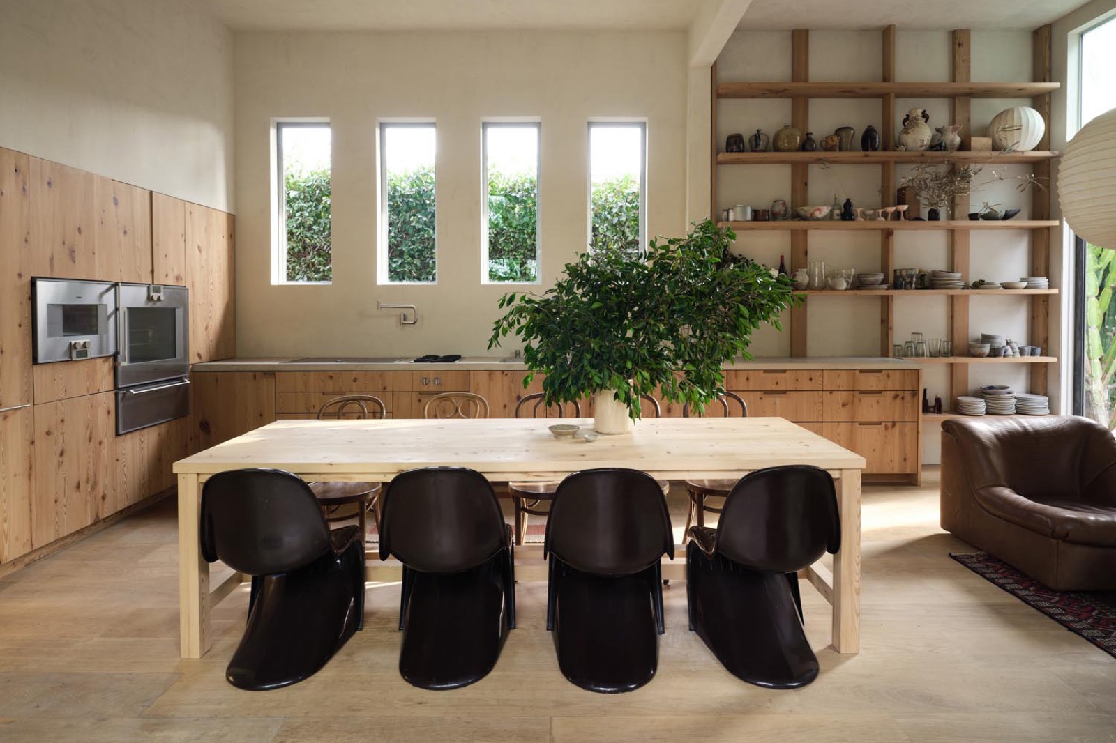 Sunset Atelier kitchen with raw pine cabinetry, concrete countertops, open shelving and garden windows — Leanne Ford production location in Venice, California