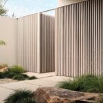 Minimalist modern home exterior with crisp white walls, cedar louvers, and lush landscaped greenery.